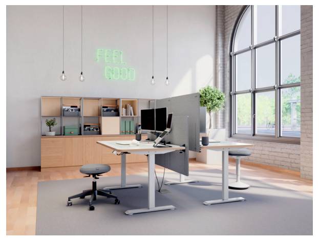 Modernes Open-Office mit höhenverstellbaren Schreibtischen, Computermonitoren, Regalen und einem leuchtenden Neon-Schild mit der Aufschrift „FEEL GOOD