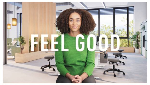 Frau im grünen Pullover sitzt in einem modernen Büro mit überlagerftem Text „FEEL GOOD