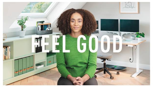 Frau im grünen Pullover sitzt in einem hellen Homeoffice mit den überlagerten Worten „FEEL GOOD