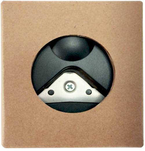 Nahaufnahme eines schwarzen und silbernen Geräteteil durch eine runde Aussparung in einer braunen Papierkiste gesehen.