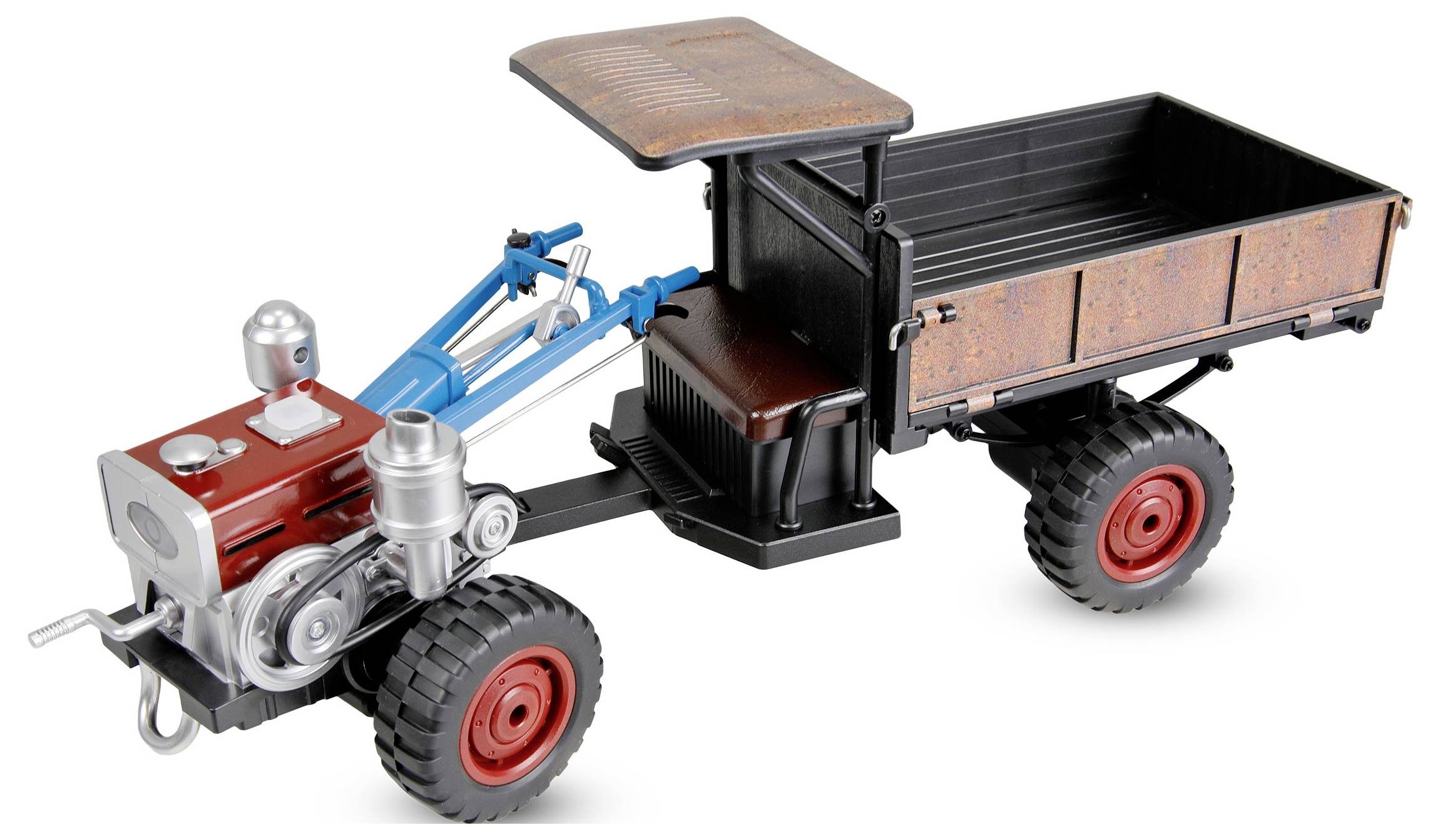 Spielzeug-Trettraktor mit Frontmotor und blauer Anhängekupplung, der einen kleinen schwarz-rostenfarben Anhänger mit Verdachung zieht.