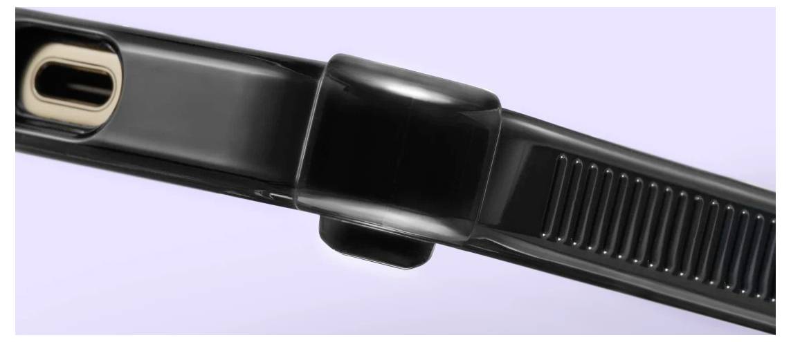 Nahaufnahme eines schwarzen Smartwatch-Armband-Verschlusses mit geripptem Armband und Metallschnalle auf hellviolettem Hintergrund.