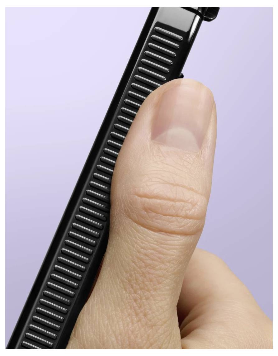 Nahaufnahme eines Daumens, der ein schwarzes geripptes tragbares Werkzeug oder Gerät gegen einen hellvioletten Hintergrund drückt.