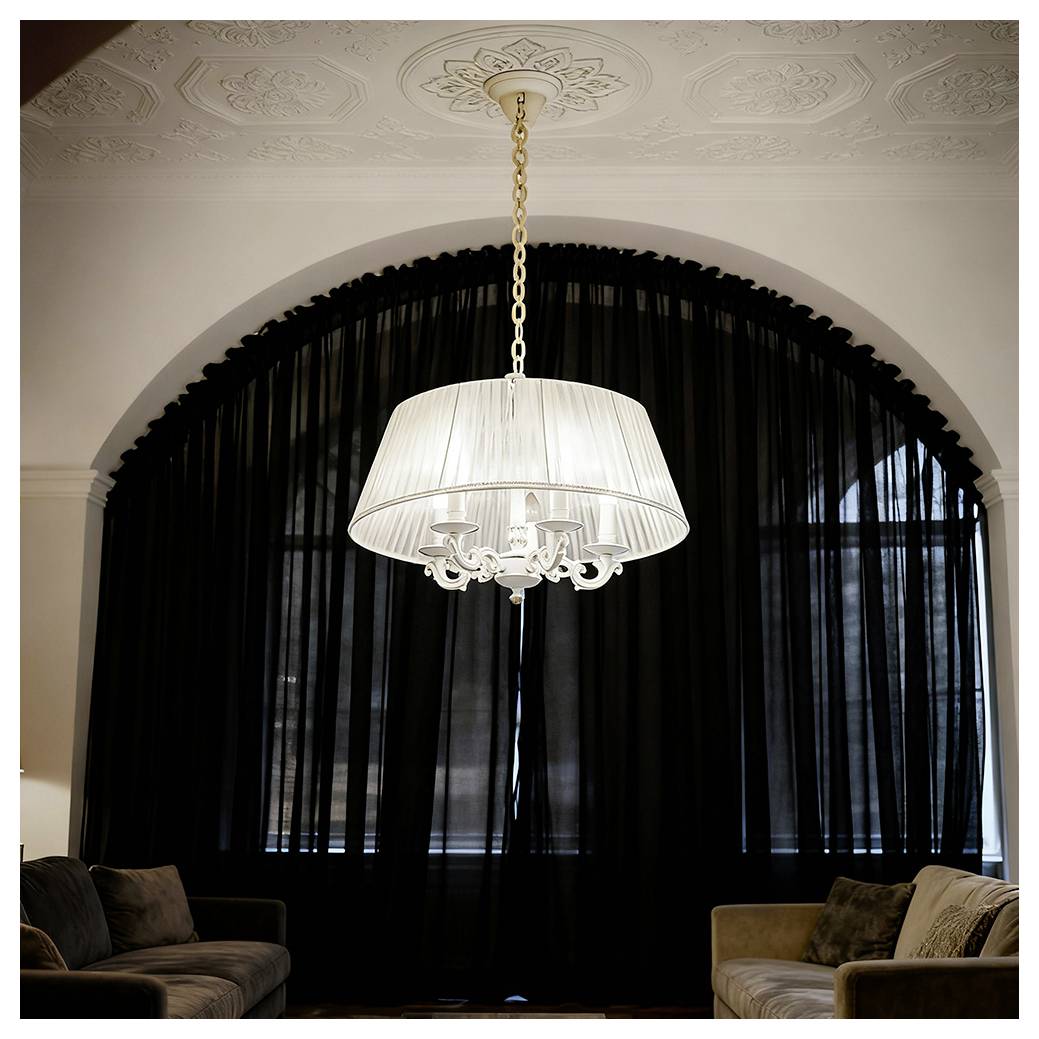 Ein weißer hängender Kronleuchter, der mittig vor einem großen Bogenfenster angebracht ist, das von schwarzen Vorhängen bedeckt wird, mit Sofas auf beiden Seiten in einem formalen Wohnzimmer.