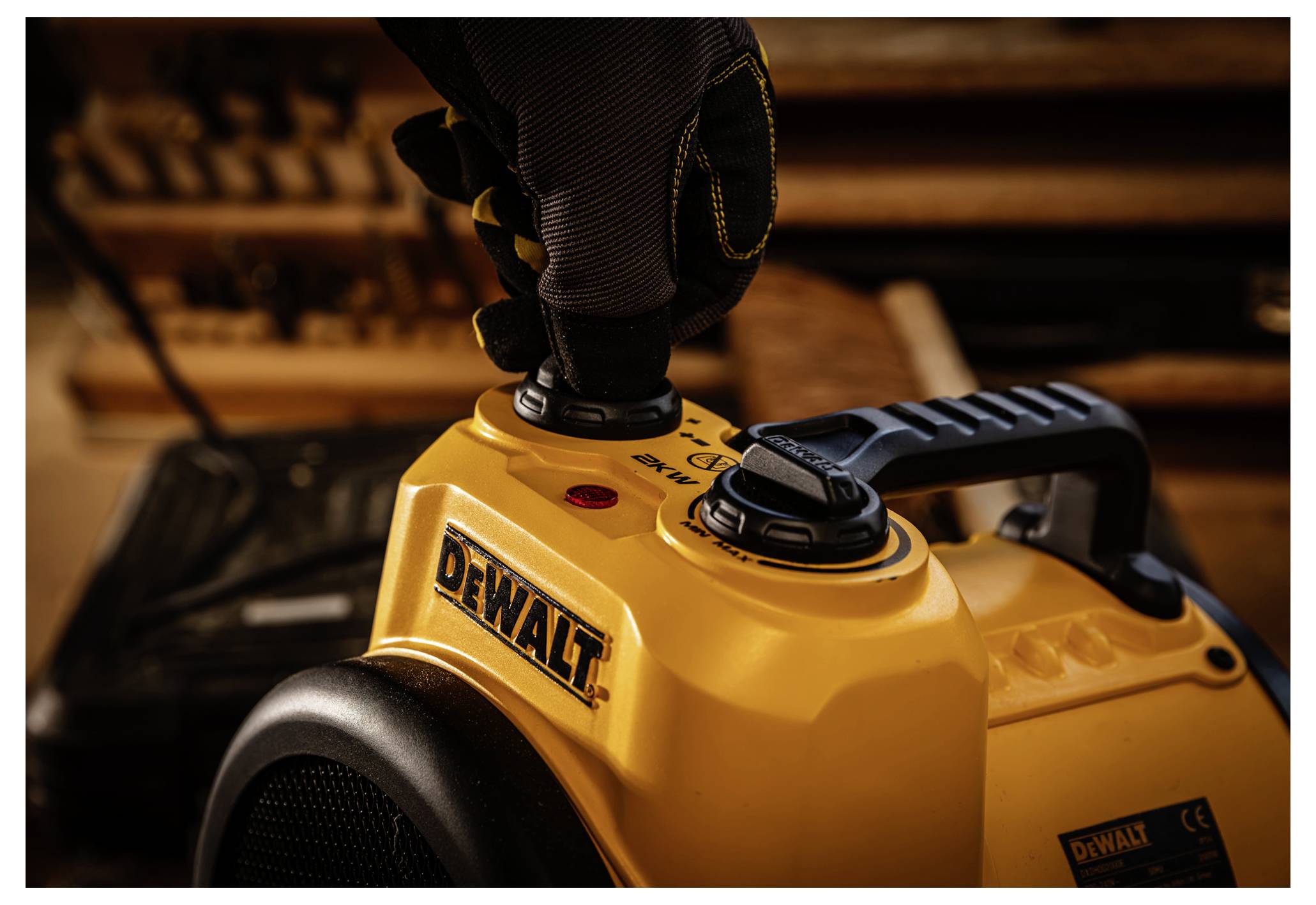 Nahaufnahme eines gelben DEWALT Elektrowerkzeugs mit einer behandschuhten Hand, die an dem oberen Bedienungsknopf eingestellt wird.