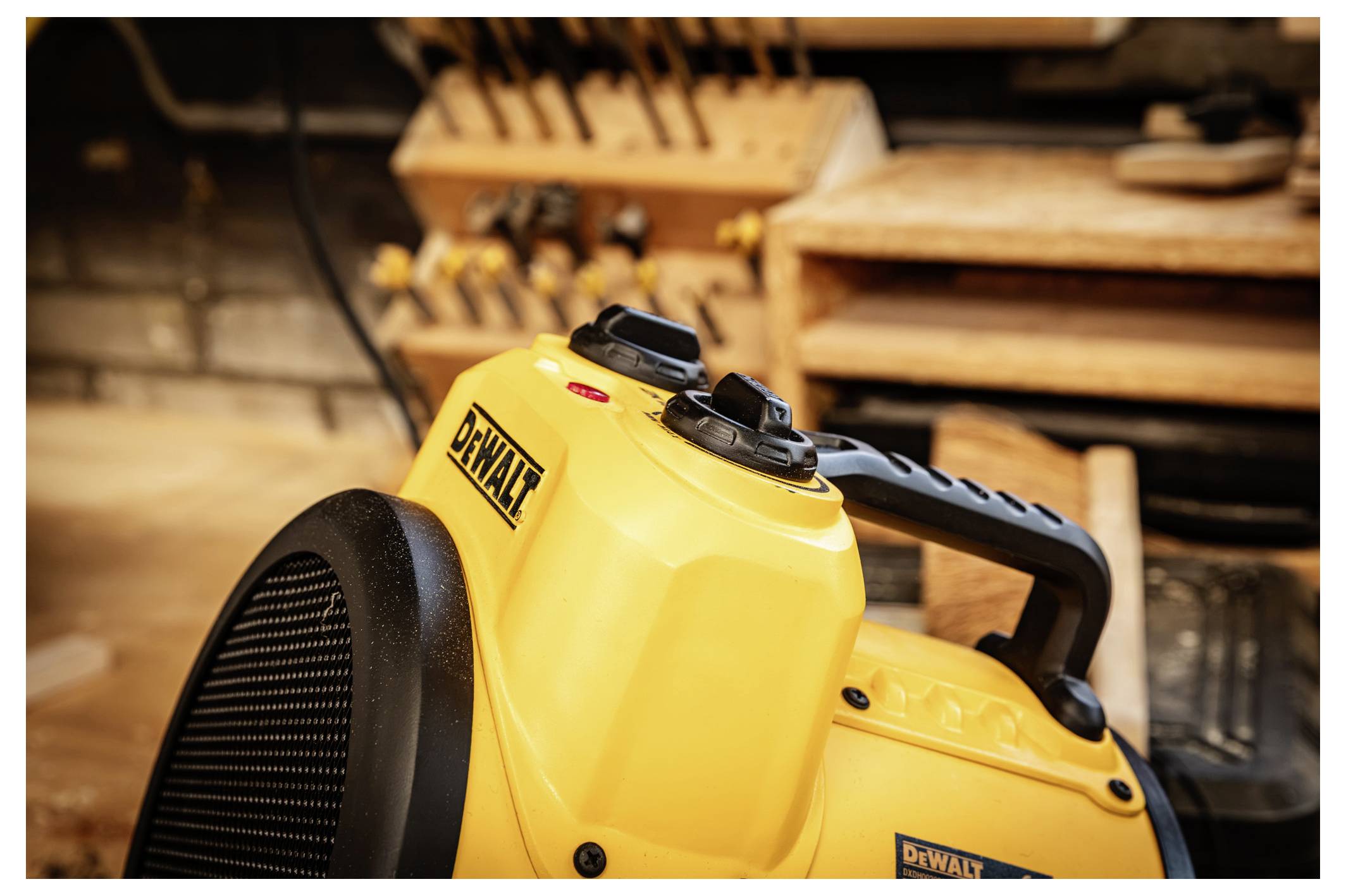 Gelber tragbarer DeWalt-Ventilator/Heizer in einer Werkstatt, mit unscharfen Werkzeugregalen im Hintergrund.