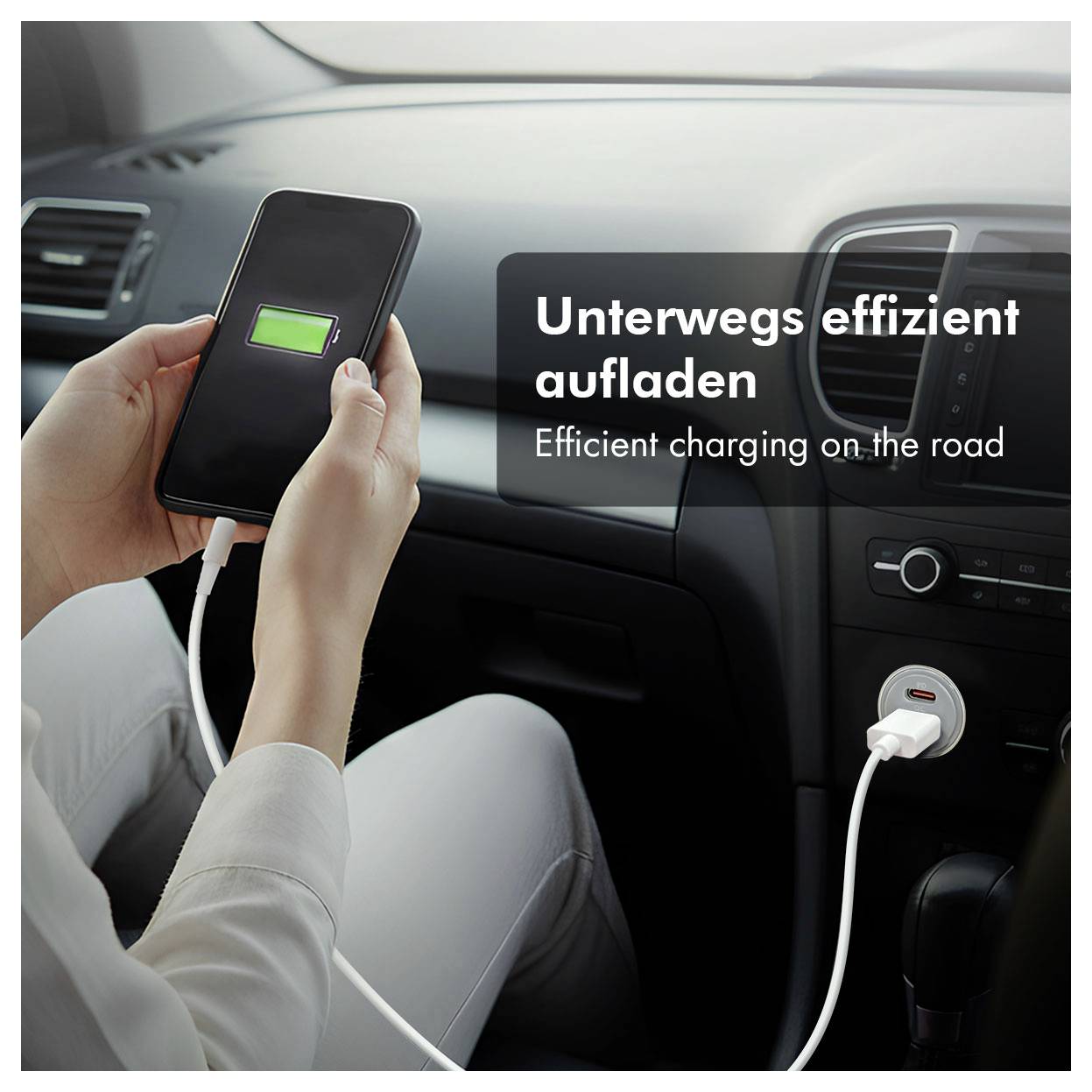 Person lädt ein Smartphone in einem Auto auf, mit dem Text „Unterwegs effizient aufladen