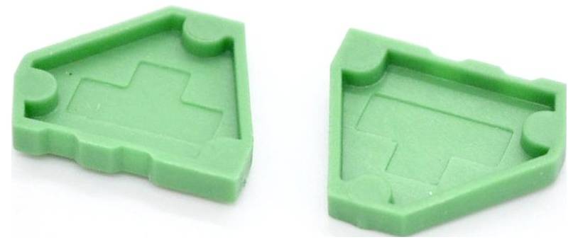 Zwei grüne Kunststoff-Puzzleteile, jeweils mit einer eingearbeiteten hausförmigen Aussparung und gezackten Kanten, nebeneinander auf weißem Hintergrund dargestellt.