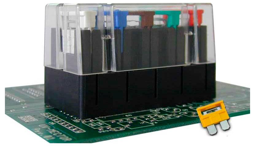 Nahaufnahme einer grünen Leiterplatte mit einem schwarzen elektrischen Relaismodul und einer kleinen gelben Komponente daneben.