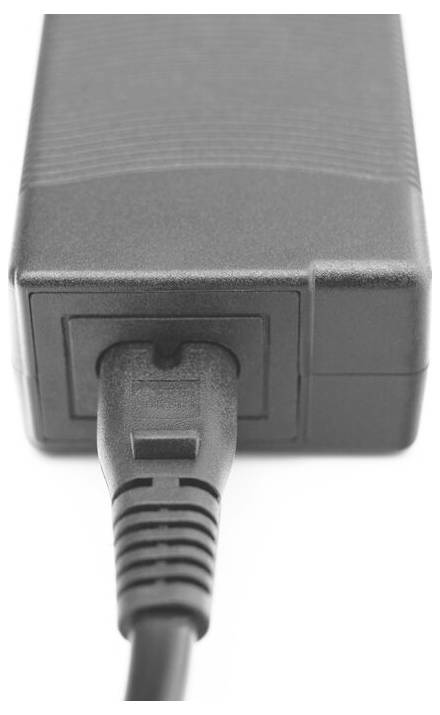 Nahaufnahme eines grauen Netzadapters mit einem Kabel, das in seine vordere Buchse gegen einen weißen Hintergrund eingesteckt ist.