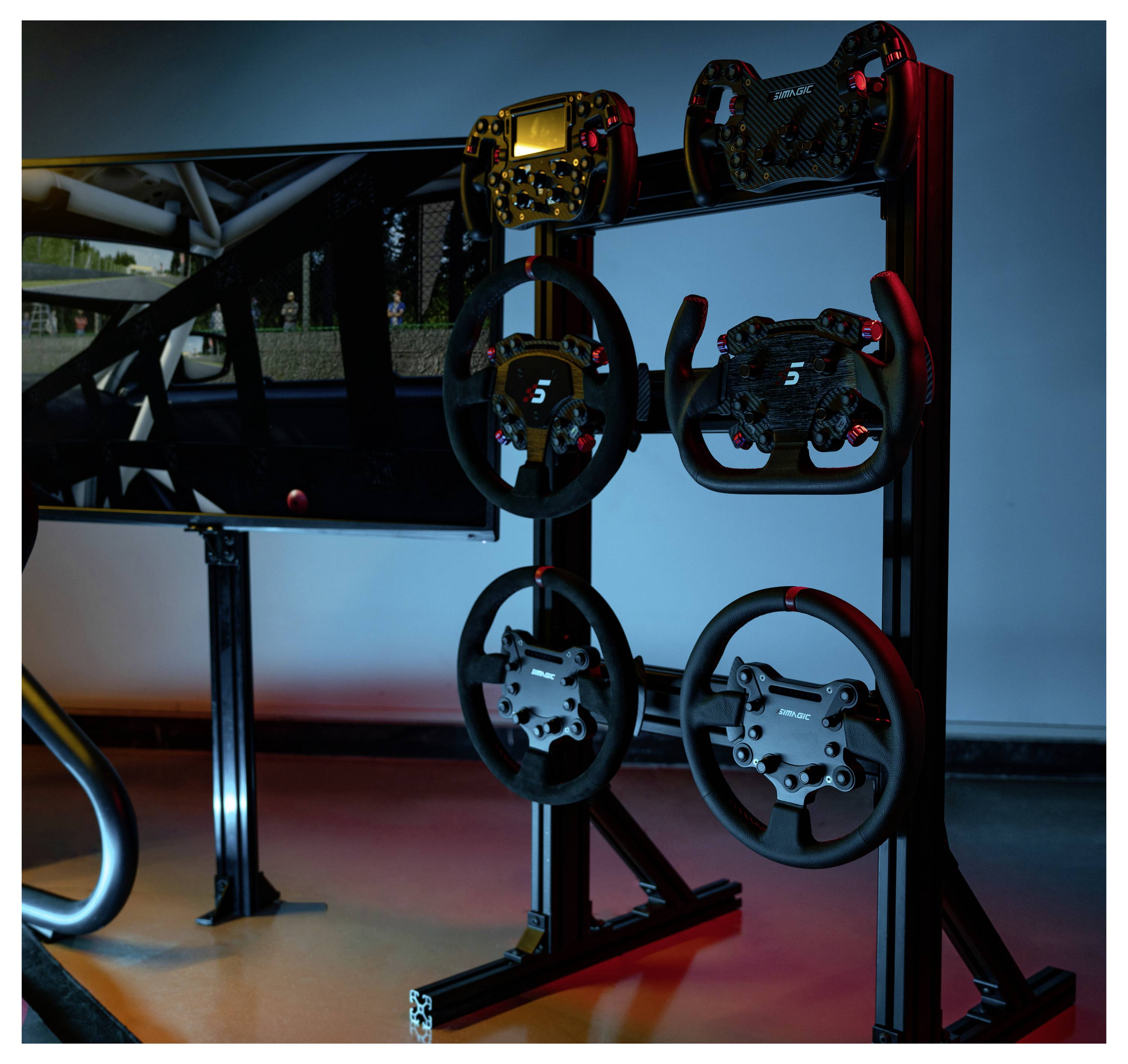 Racing-Simulator-Display mit mehreren Lenkrädern, die auf einem Ständer neben einem Monitor montiert sind, beleuchtet durch blaue und rote Akzentlichter.