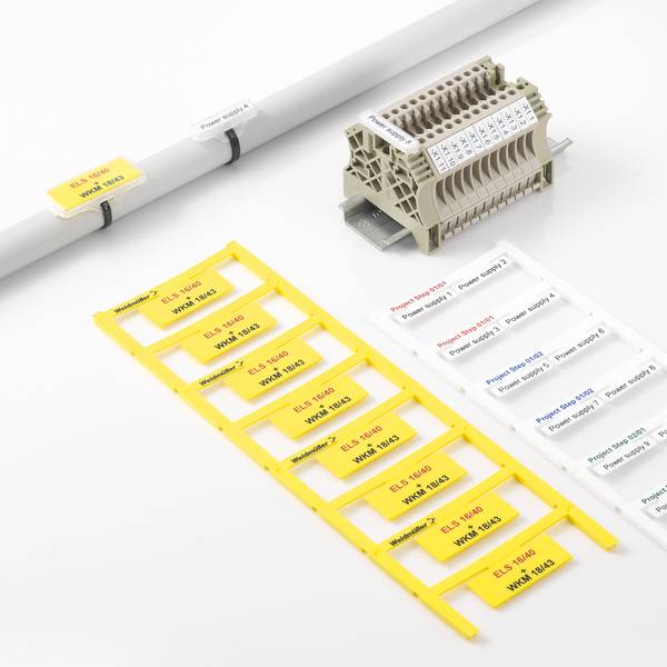 Kabel- und Klemmleistenetiketten auf einer weißen Oberfläche angeordnet, mit gelben und weißen Identifikationsschildern für Drähte und einem Steckerblock mit beschrifteten Slots.