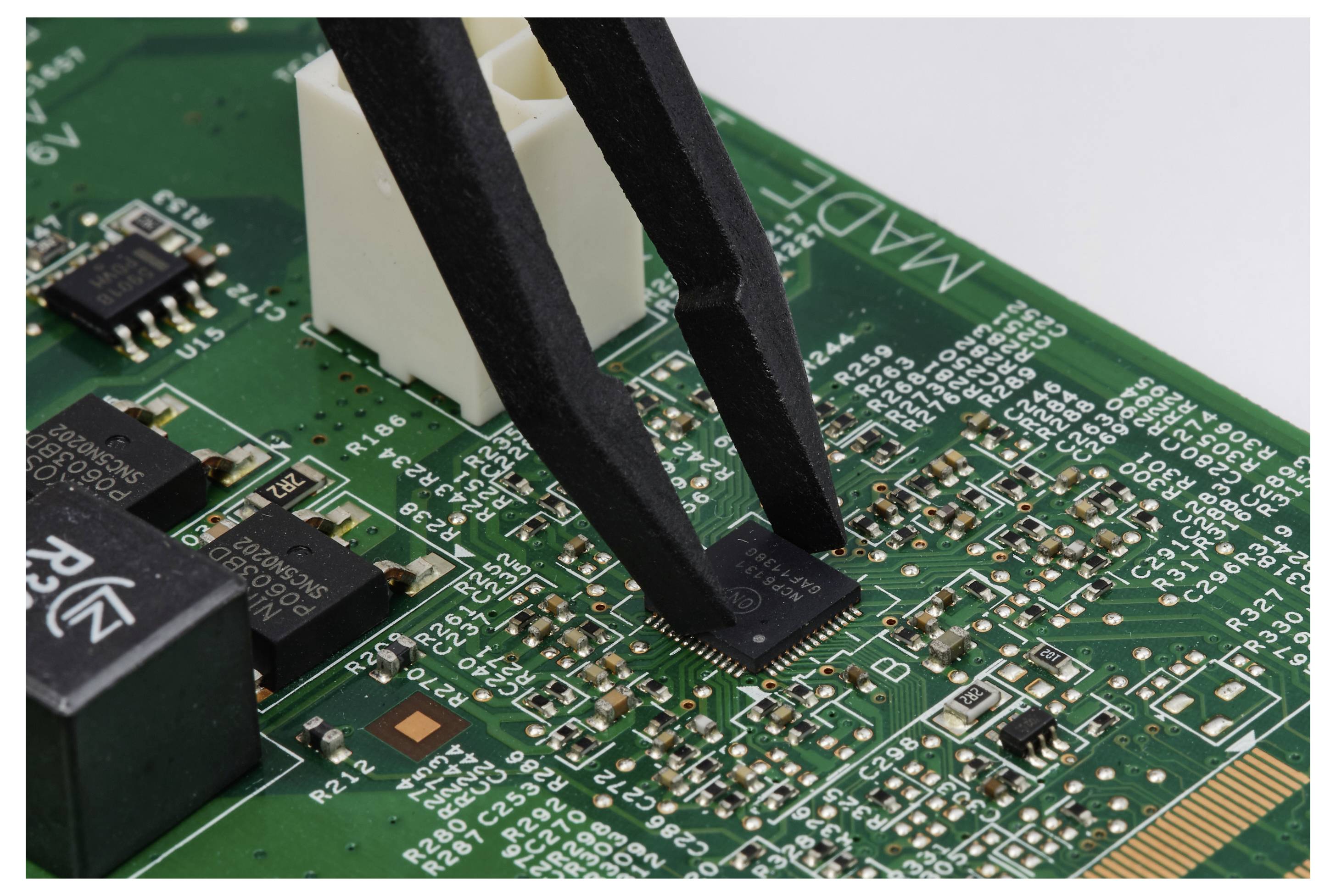Pinzetten platzieren einen winzigen Chip auf einer grünen Leiterplatte während der Elektronikbestückung.