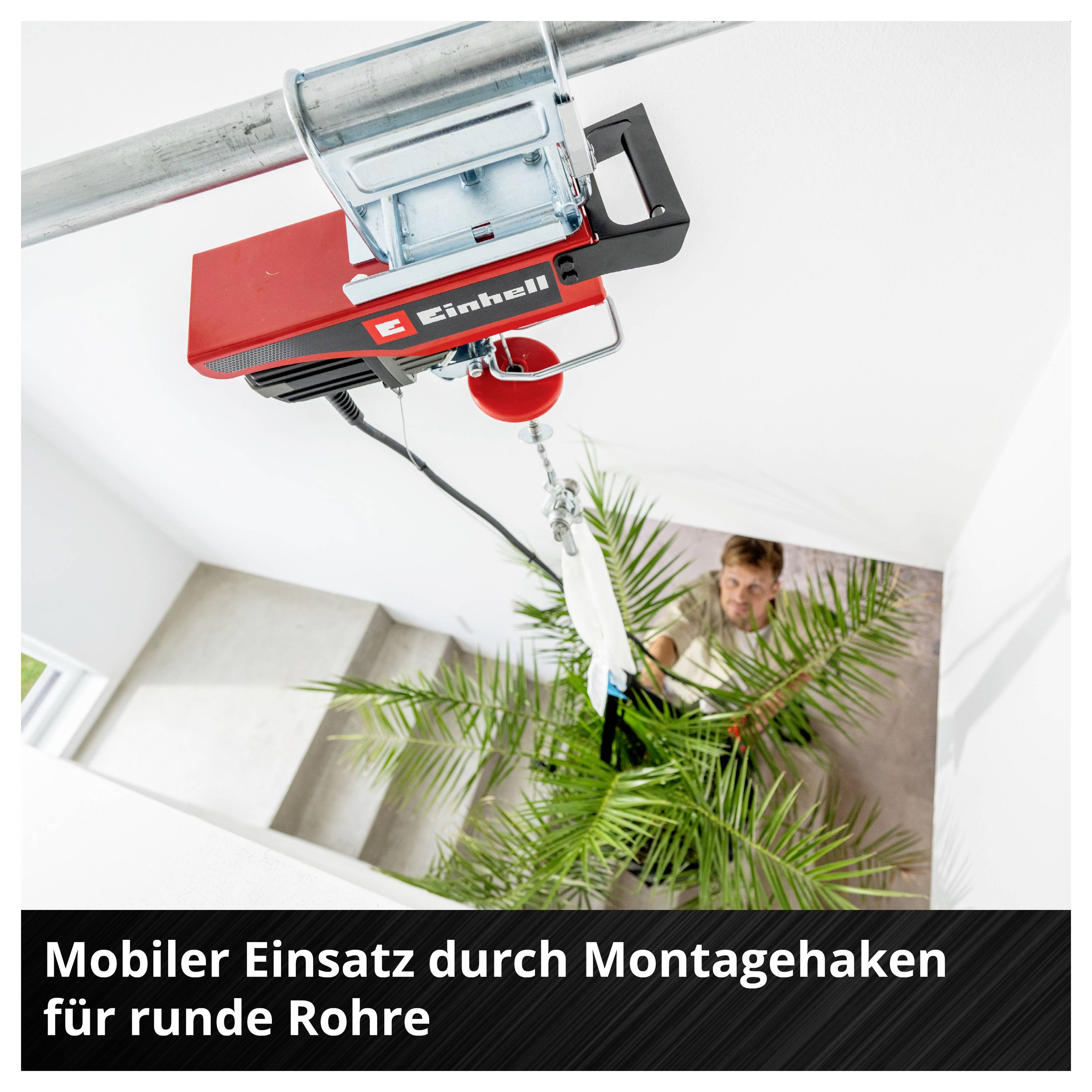 Montagehaken an rundem Rohr befestigt, hebt eine Elektroseilwinde eine Pflanze in ein Treppenhaus; Text: 'Mobiler Einsatz durch Montagehaken für runde Rohre'