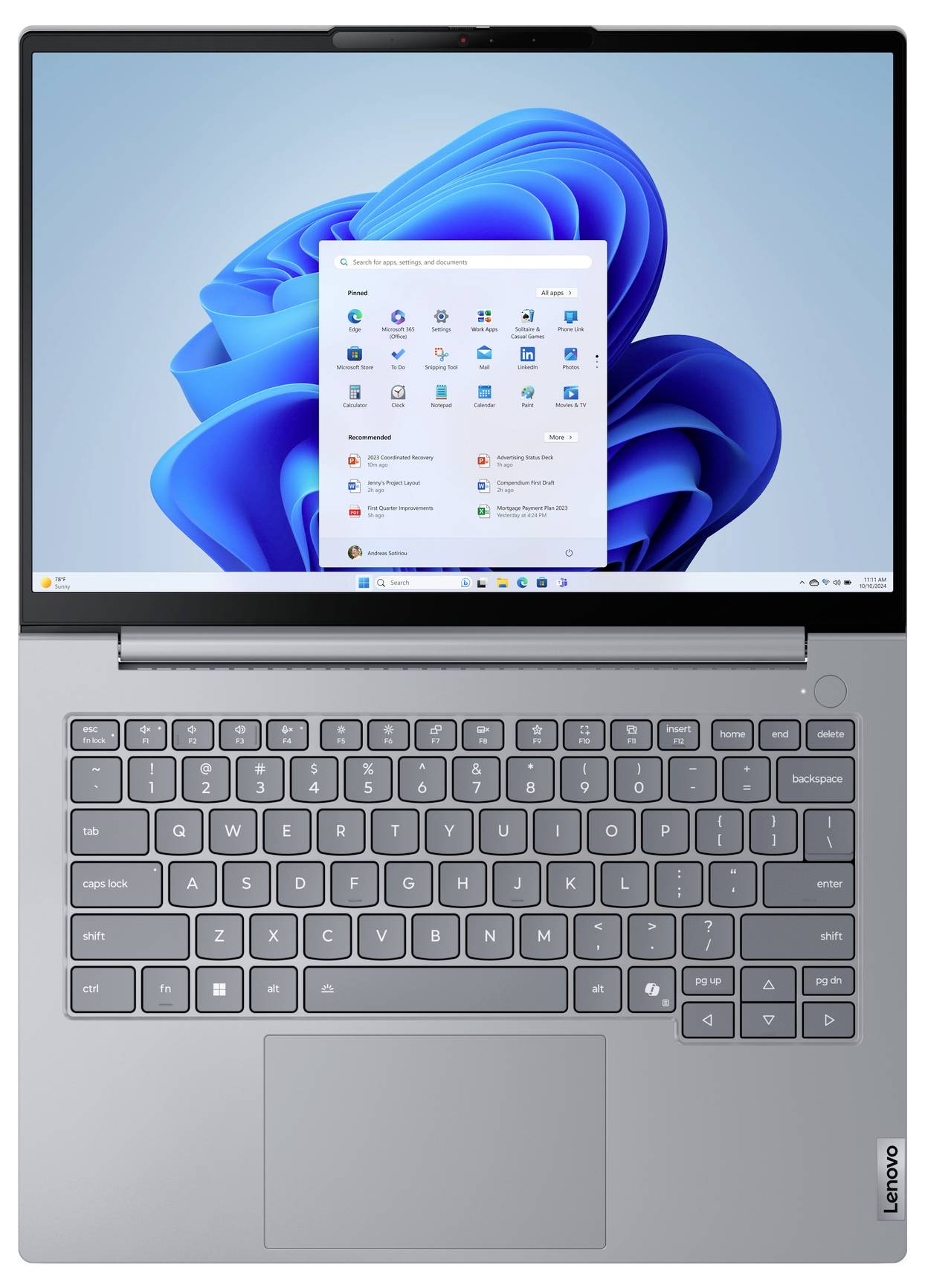 Grauer Lenovo-Laptop mit Windows 11, das auf dem Desktop geöffnet ist und das zentrierte Startmenü über der blauen abstrakten Tapete anzeigt.