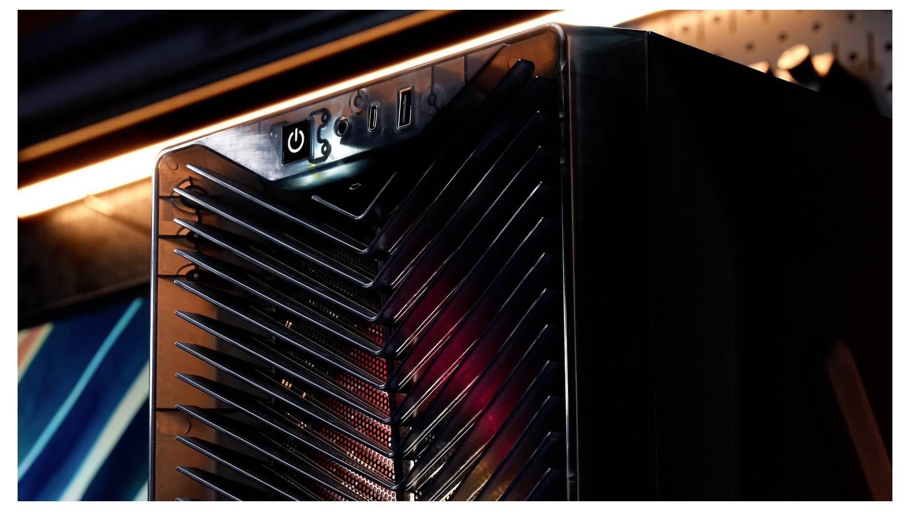 Nahaufnahme eines schwarzen Computer-Towers oder Server-Gehäuses mit beleuchtetem Netzschalter und Lamellenfrontblende, gezeigt in einer dunkel beleuchteten Umgebung.