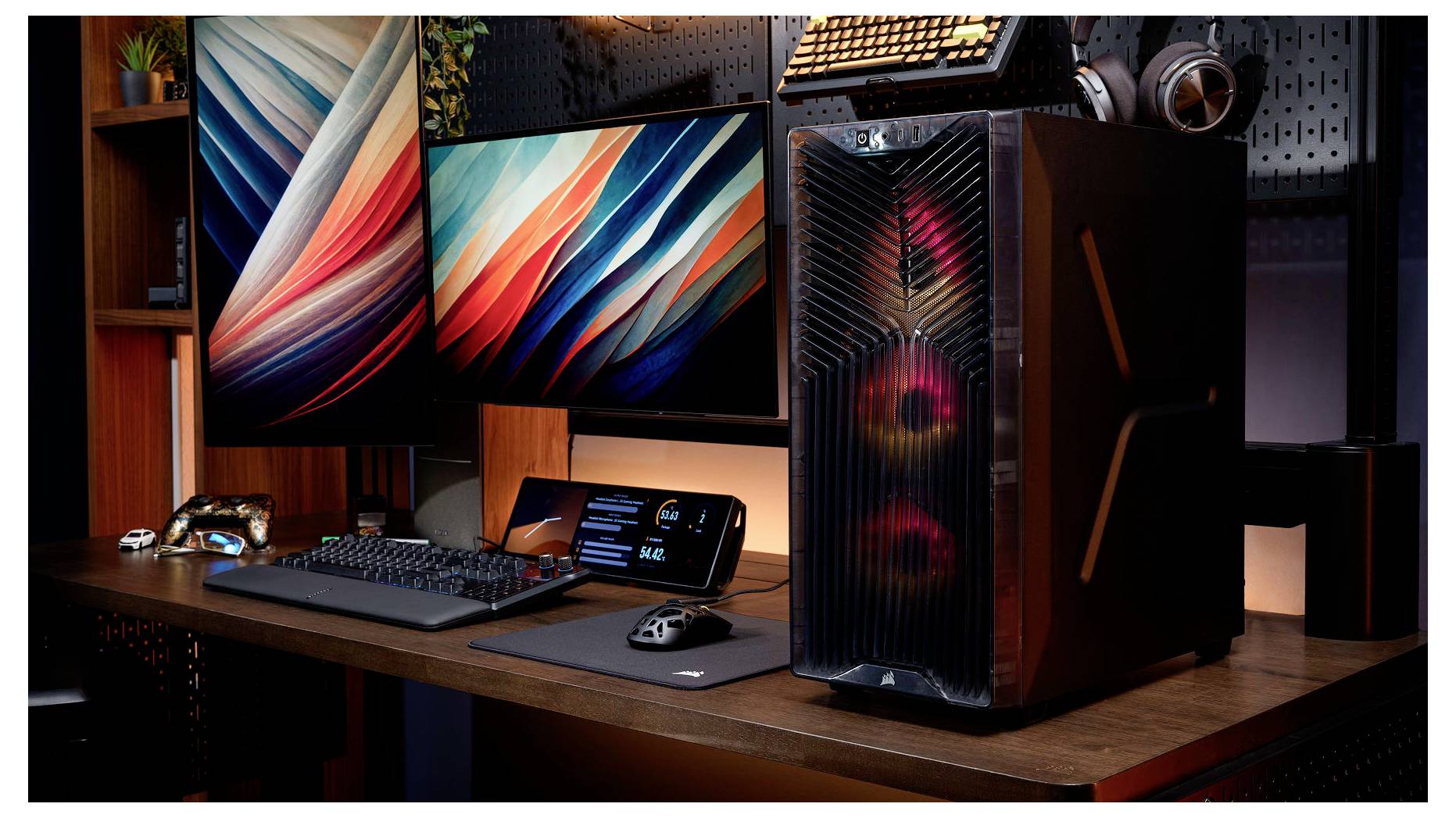 Hochwertiges Gaming-Setup für den Desktop mit zwei Monitoren, RGB-beleuchteter PC-Tower, Tastatur, Maus und Kopfhörern auf einem Holzschreibtisch.