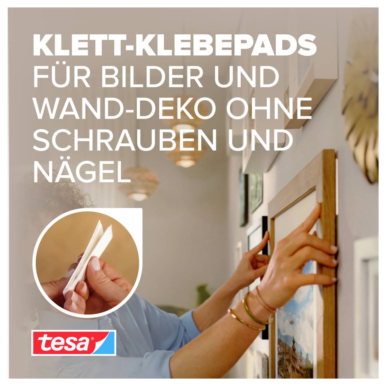 Tesa Klebestreifen zum Aufhängen von Bildern und Wanddekoration ohne Schrauben oder Nägel, gezeigt mit Händen, die ein gerahmtes Bild anbringen.