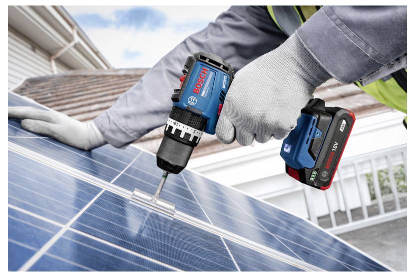 Arbeiter, der einen kabellosen Bosch-Bohrschrauber verwendet, um Solarpanele auf einem Dach zu befestigen.
