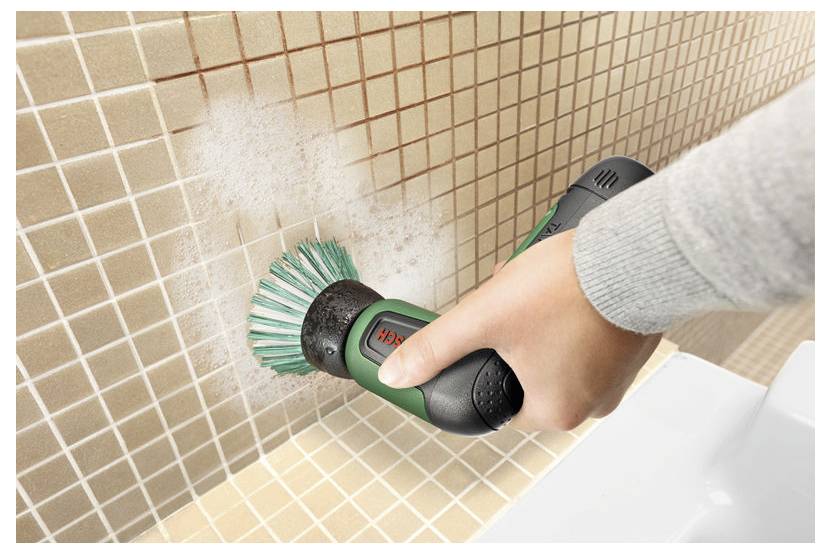 Person using a handheld electric scrub brush to clean dirty tile grout in a bathroom or shower corner.---Person, der eine tragbare elektrische Scheuerbürste verwendet, um schmutzige Fliesenfugen in einer Badezimmer- oder Duschkante zu reinigen.