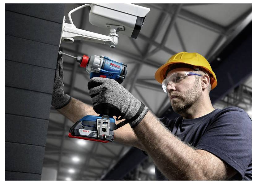 Bauarbeiter mit Schutzhelm und Schutzbrille, der einen Bosch-Elektroschrauber und eine Stichsäge verwendet, um ein an der Wand montiertes Gerät im Innenbereich zu installieren.