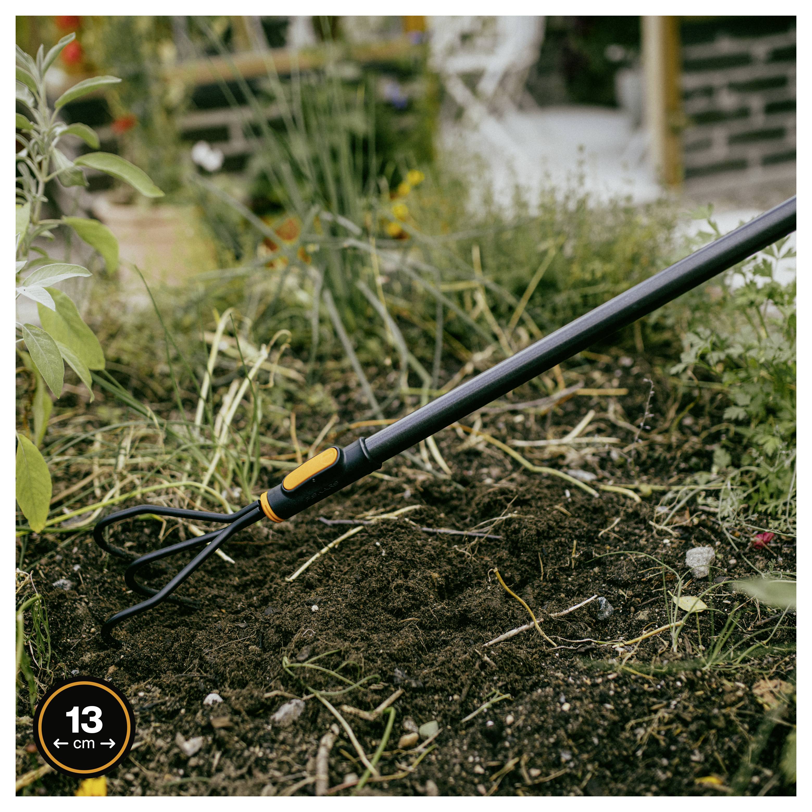 Gartenhaue oder Kultivator-Werkzeug liegt auf Erde in einem Gartenbeet, mit einem Messsymbol von 