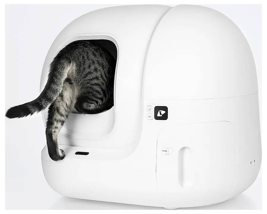 Katze, die in eine weiße, geschlossene, selbstreinigende Katzentoilette eindringt, wobei ihr Schwanz und ihre Hinterbeine aus der Öffnung herausstehen.