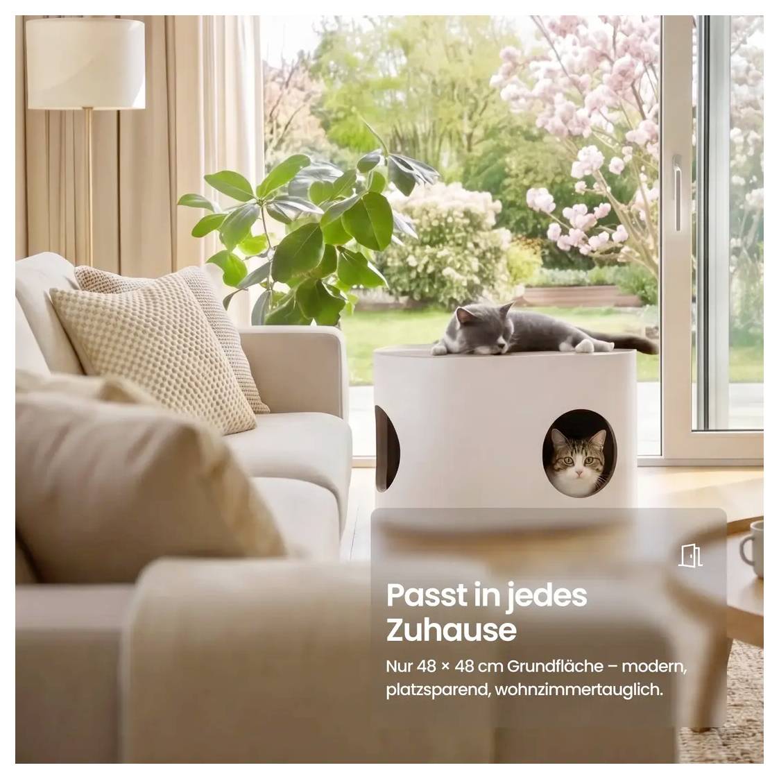 Gemütliches Wohnzimmer mit Katzen, die ein kompaktes modernes Katzenhaus am Fenster nutzen; der Text sagt „Passt in jedes Zuhause