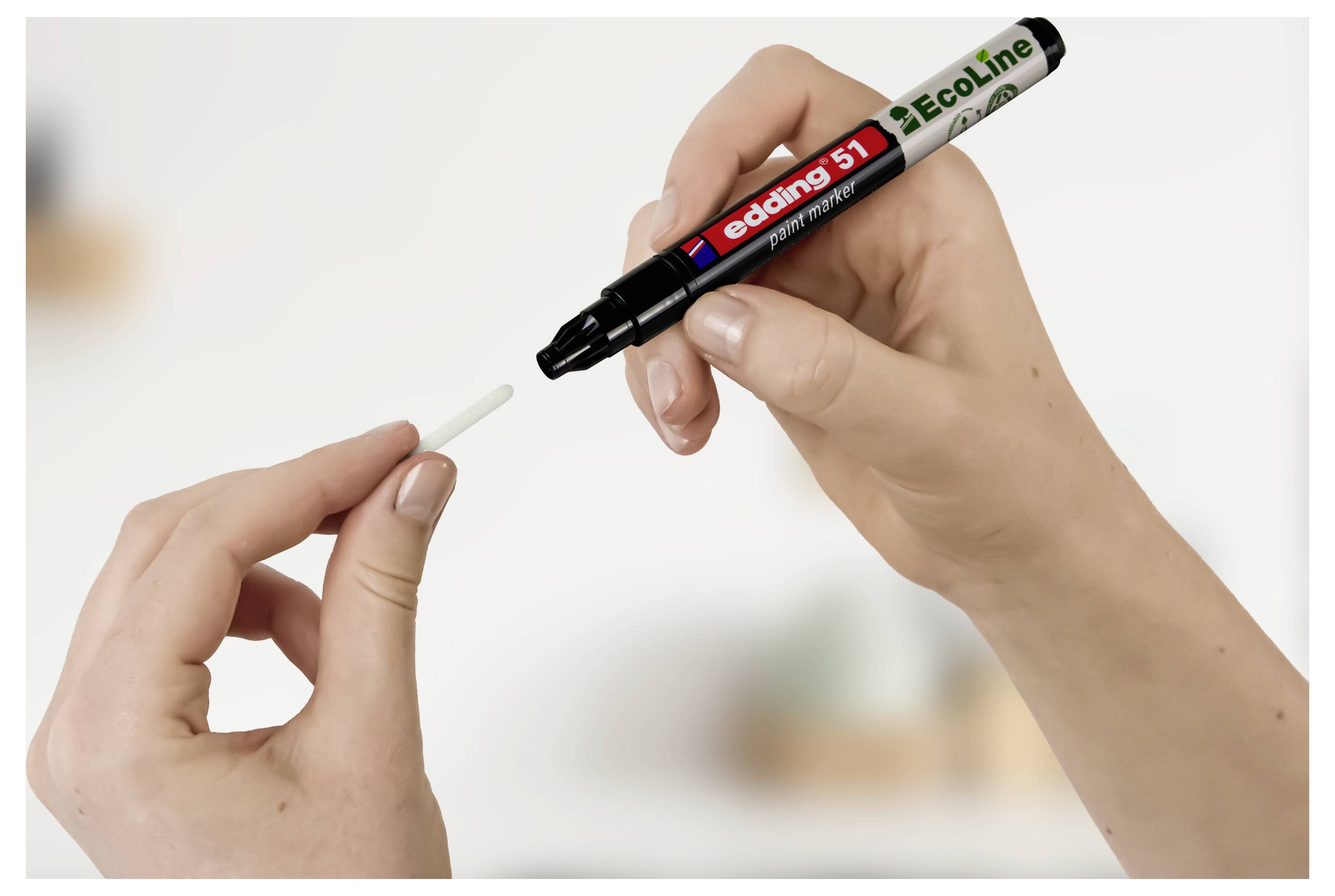 Hände halten einen schwarzen Edding Ecoline Marker und dessen Kappe, wobei die Kappe von der Stiftspitze abgenommen wird.