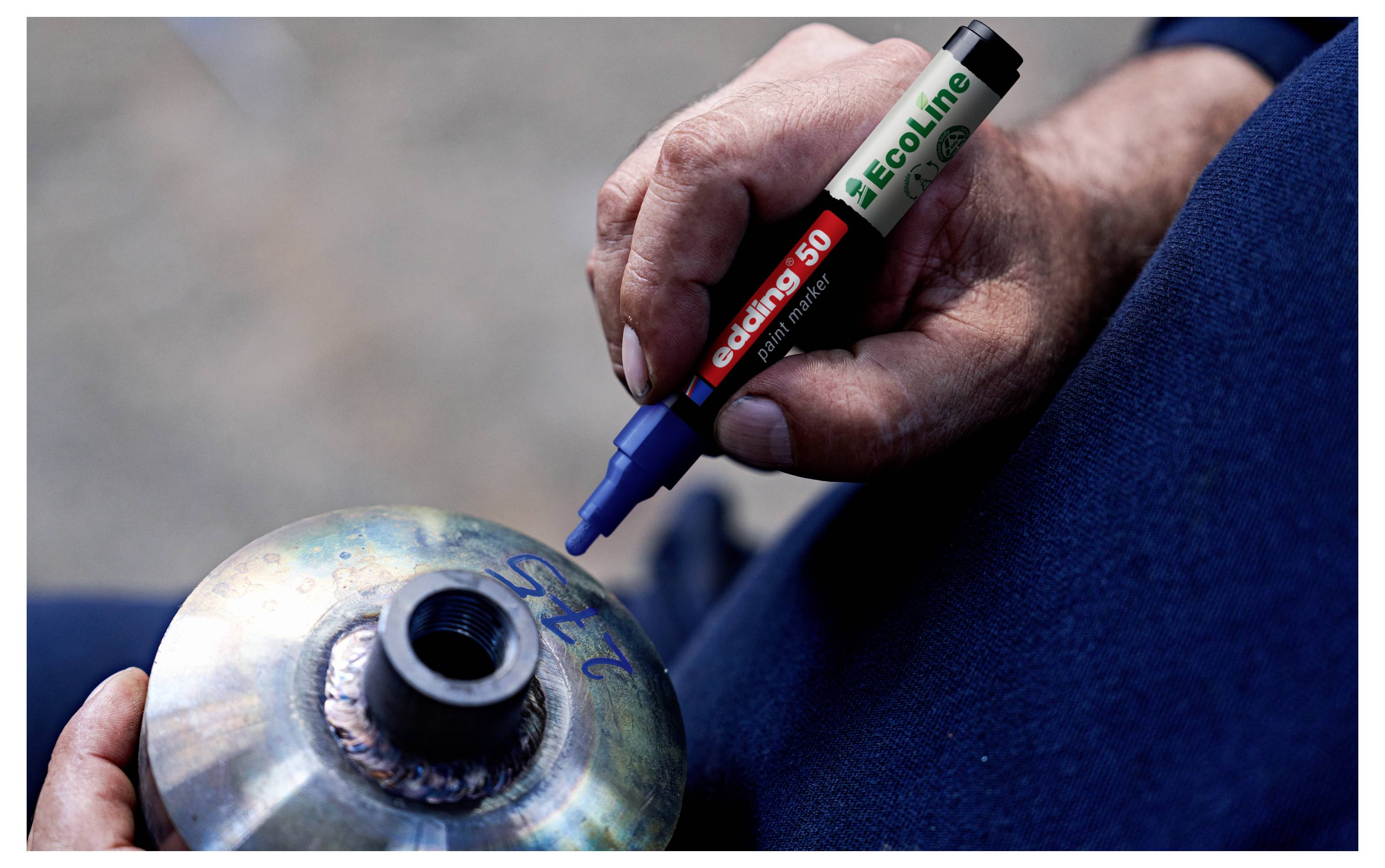 Handmarkierung eines Metallzylinders mit einem blauen Permanentmarker, wahrscheinlich zum Kennzeichnen eines geschweißten Teils oder einer Inspektionsmarke.