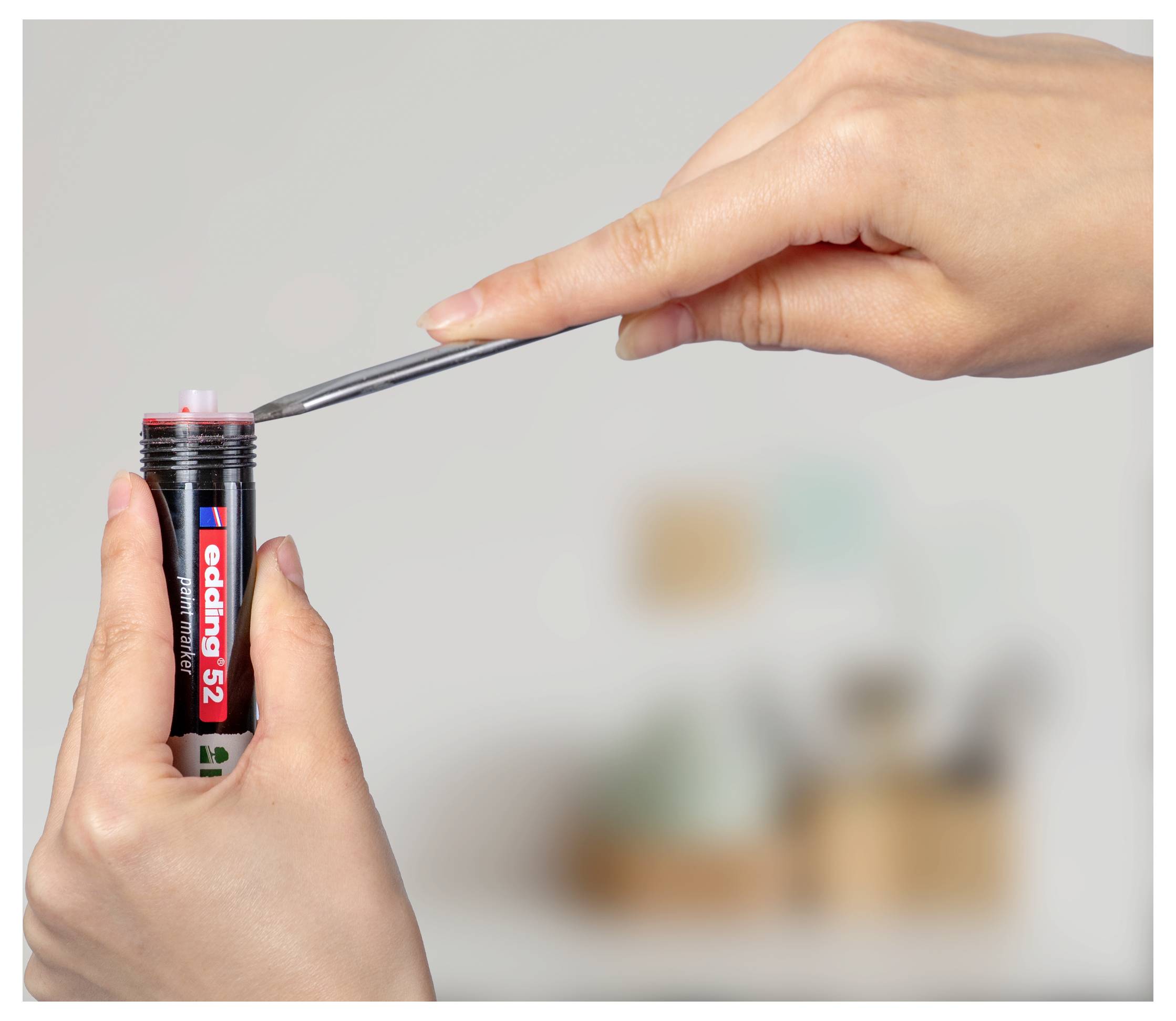 Eine Hand verwendet eine Pinzette, um eine Hörgerätebatterie aus einem kleinen Batteriegehäuse mit der Aufschrift „Energizer 312