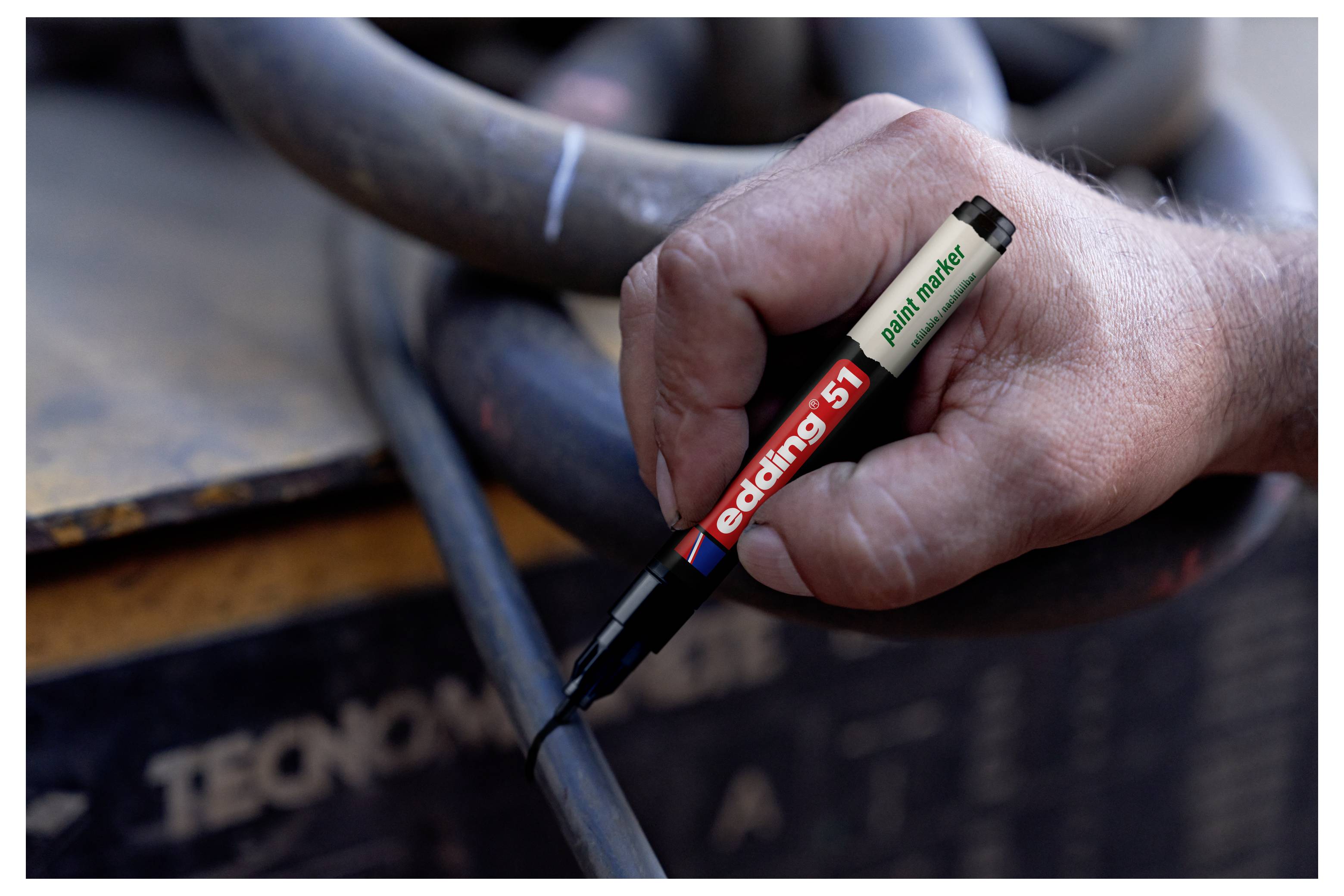Hand, die einen weißen Lackmarker mit der Aufschrift "edding 55" hält, um ein schwarzes Kabel oder einen schwarzen Schlauch zu markieren