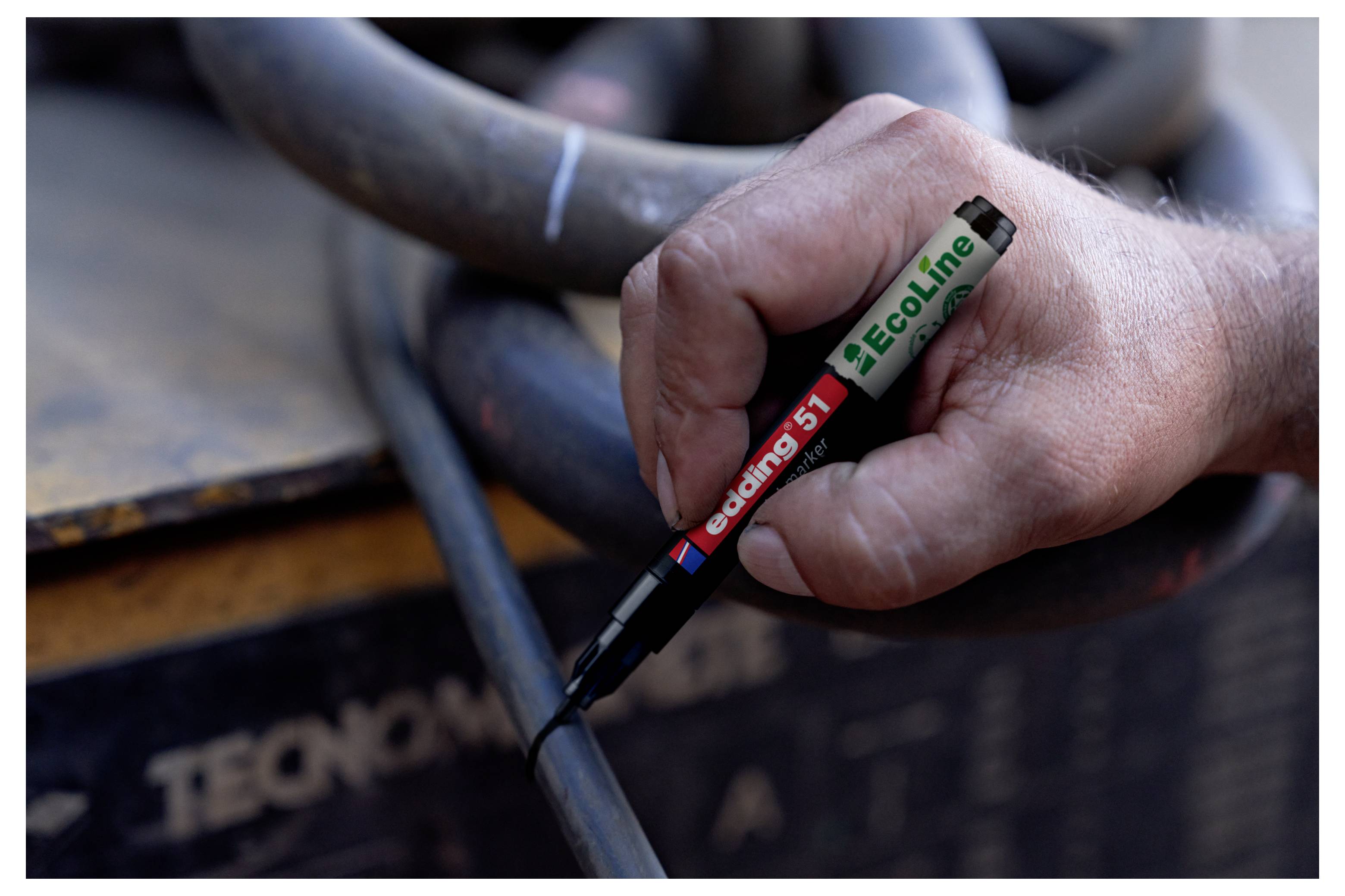 Nahaufnahme einer Hand, die mit einem schwarzen Marker auf ein Kabel oder einen Schlauch schreibt, wobei auf dem Stift „ecoLine