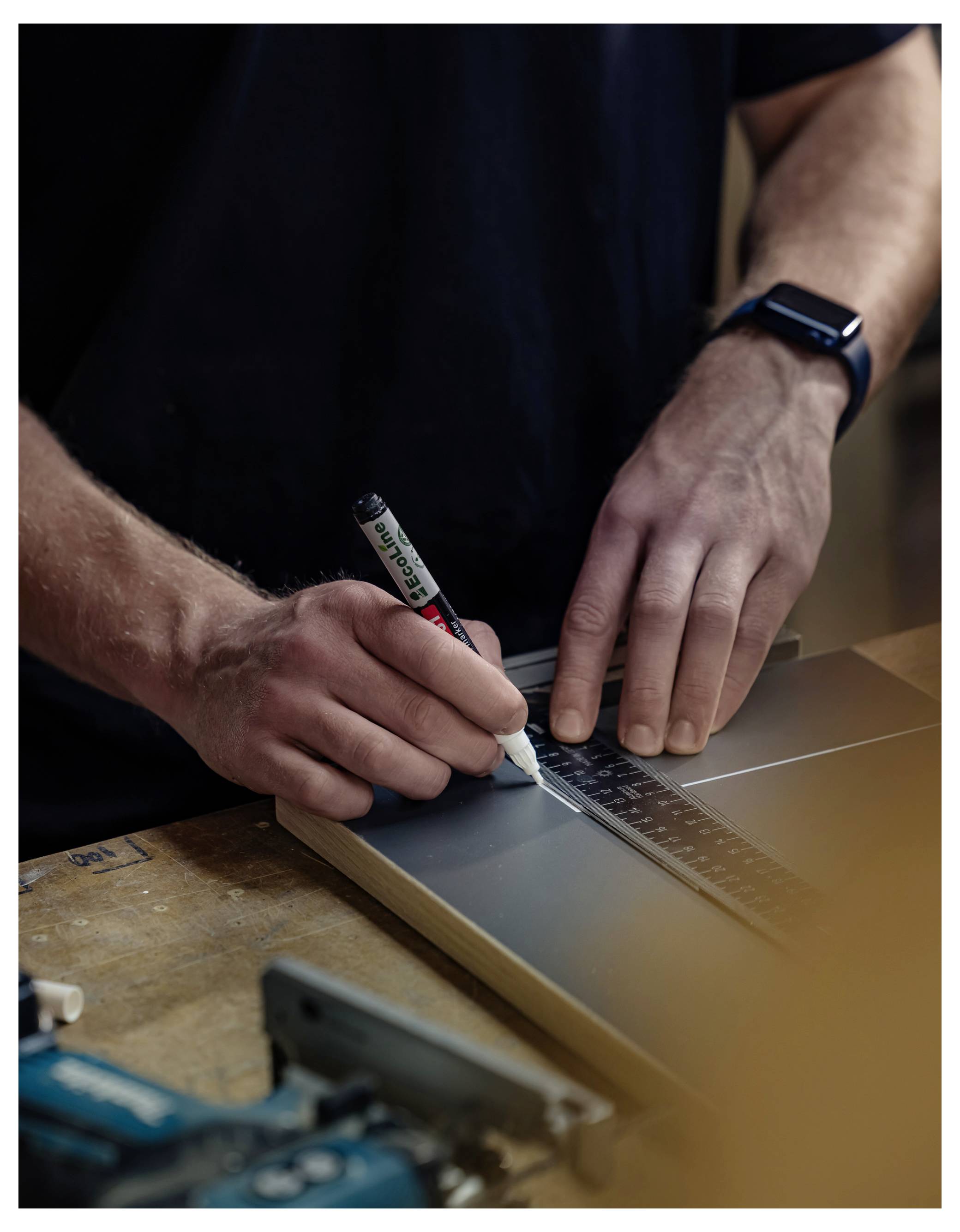 Eine Person markiert Messwerte auf der Oberseite eines Laptop-Gehäuses mit einem weißen Marker, während sie ein Lineal verwendet. Dies deutet auf einen Reparatur- oder Modifikationsprozess hin.