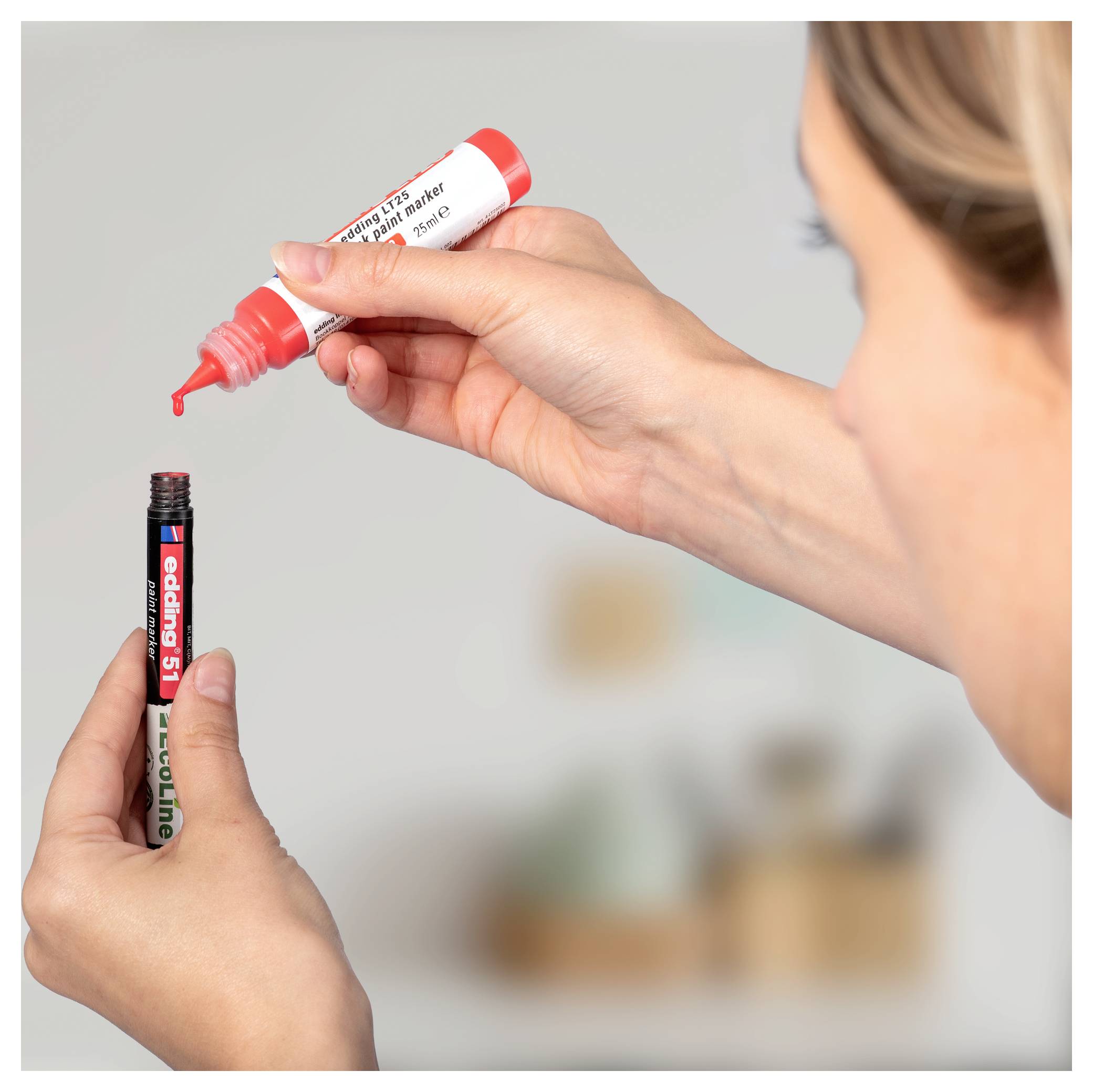 Hände füllen und schließen einen Marker mit roter Kappe mit roter Tinte in einer Nahaufnahme einer Bastelszene.