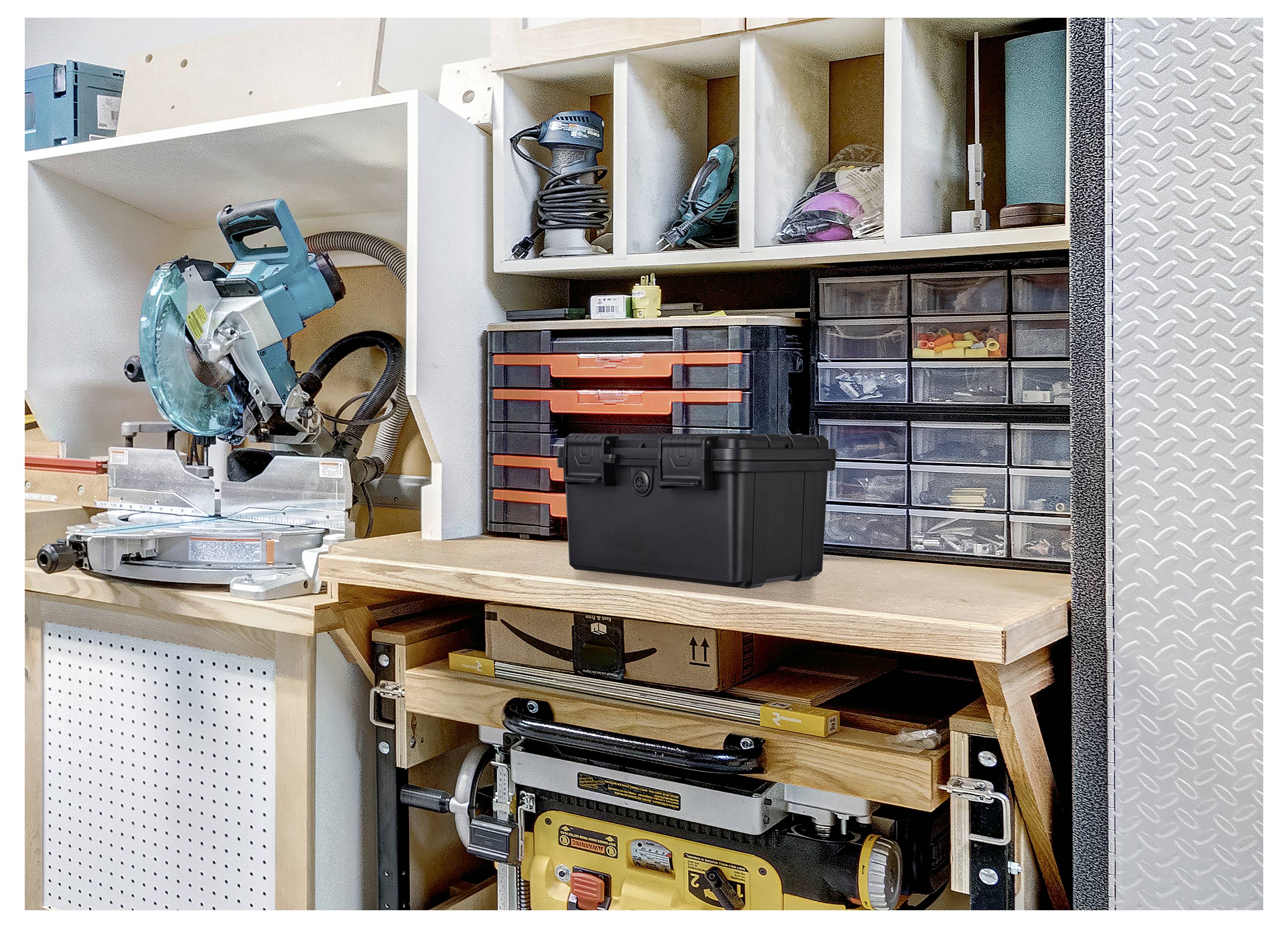 Arbeitstisch in einer Garagenwerkstatt mit einer Kappsäge, Werkzeuglagerungsbehältern und organisierten Regalen für Elektrowerkzeuge und Zubehör.