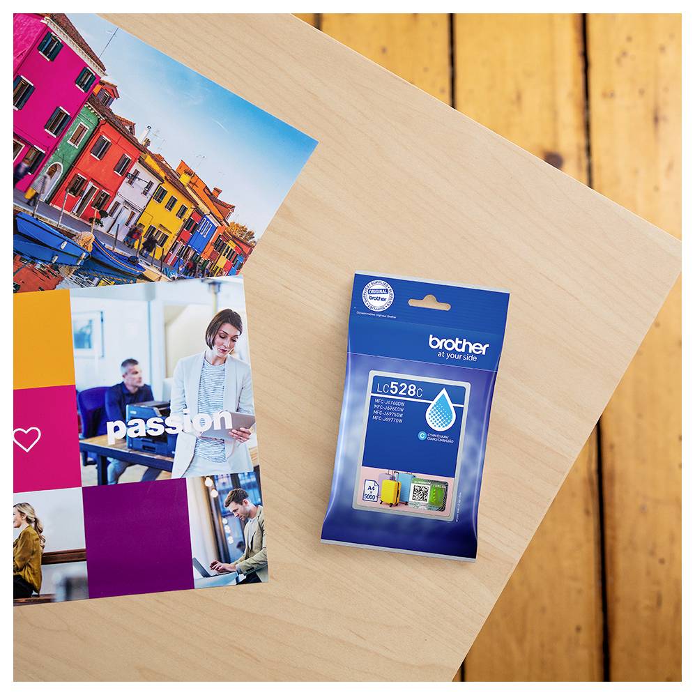 Brother LC5280 Tintenpatrone neben bunten Reise- und Bürofotodrucken auf einem Holztisch