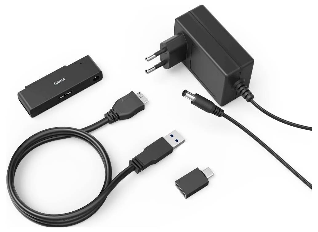 Kit mit schwarzem elektronischem Adapter mit Stromversorgung, USB-Kabel und austauschbaren Steckern/Adaptern auf weißem Hintergrund.