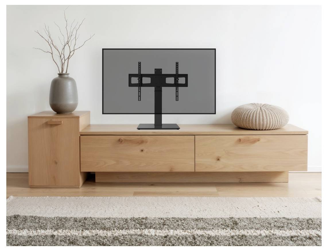Flachbildfernseher auf einer niedrigen hölzernen Medienkonsole, mit einer Vase mit Ästen auf der linken Seite und einem runden Kissen auf der rechten Seite in einem minimalistischen Wohnzimmer.