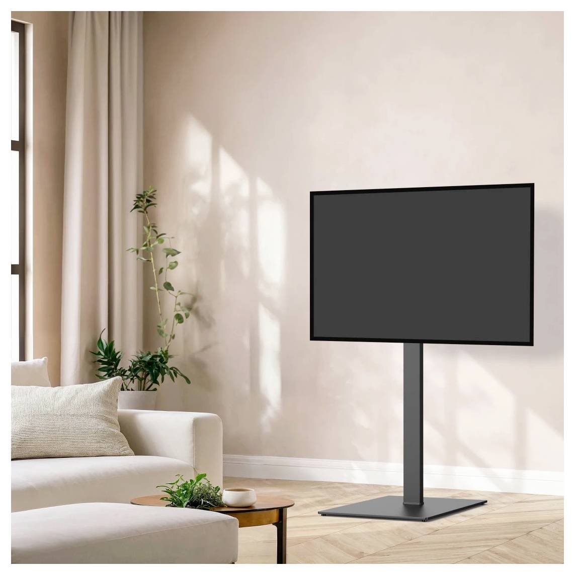 Flacher Fernseher auf einem Ständer in einem hellen, minimalistischen Wohnzimmer neben einem Sofa, Couchtisch und Topfpflanzen.
