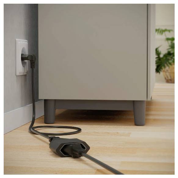 Schwarzes Stromkabel, das in eine Wandsteckdose neben einem Schrank eingesteckt ist, wobei das Kabel über einen Holzboden verläuft.