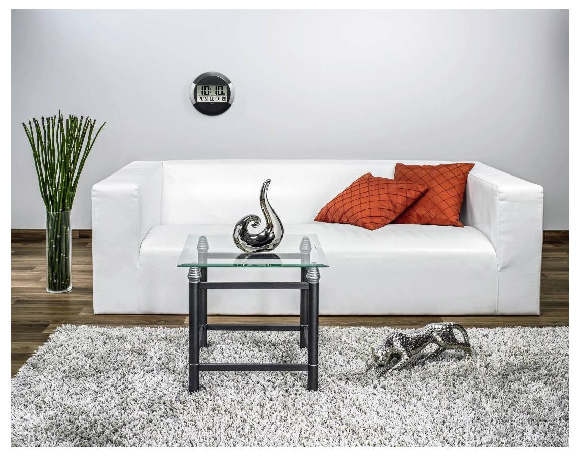 Modernes Wohnzimmer mit weißem Sofa, orangefarbenen Kissen, Glaskaffeetisch, dekorativer Skulptur, hoher Vase mit Blumen und Shag-Teppich.