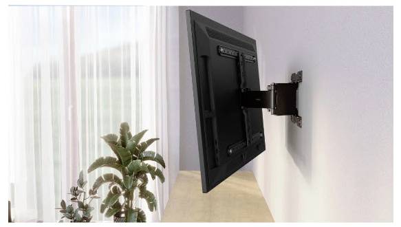 Flachbildfernseher an einer Wand mit ausziehbarem Schwenkarm montiert, von der Seite über einer Holzoberfläche in der Nähe eines Fensters und von Pflanzen betrachtet.