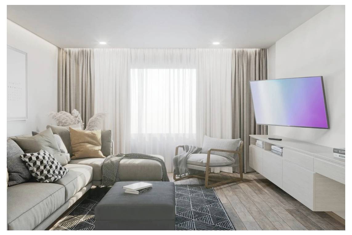 Modernes Wohnzimmer mit einem Ecksofa, einem Ottomane, einem Sessel und einem an der Wand montierten Fernseher auf einer weißen Medienkommode vor einem hellen Fenster und Vorhängen.