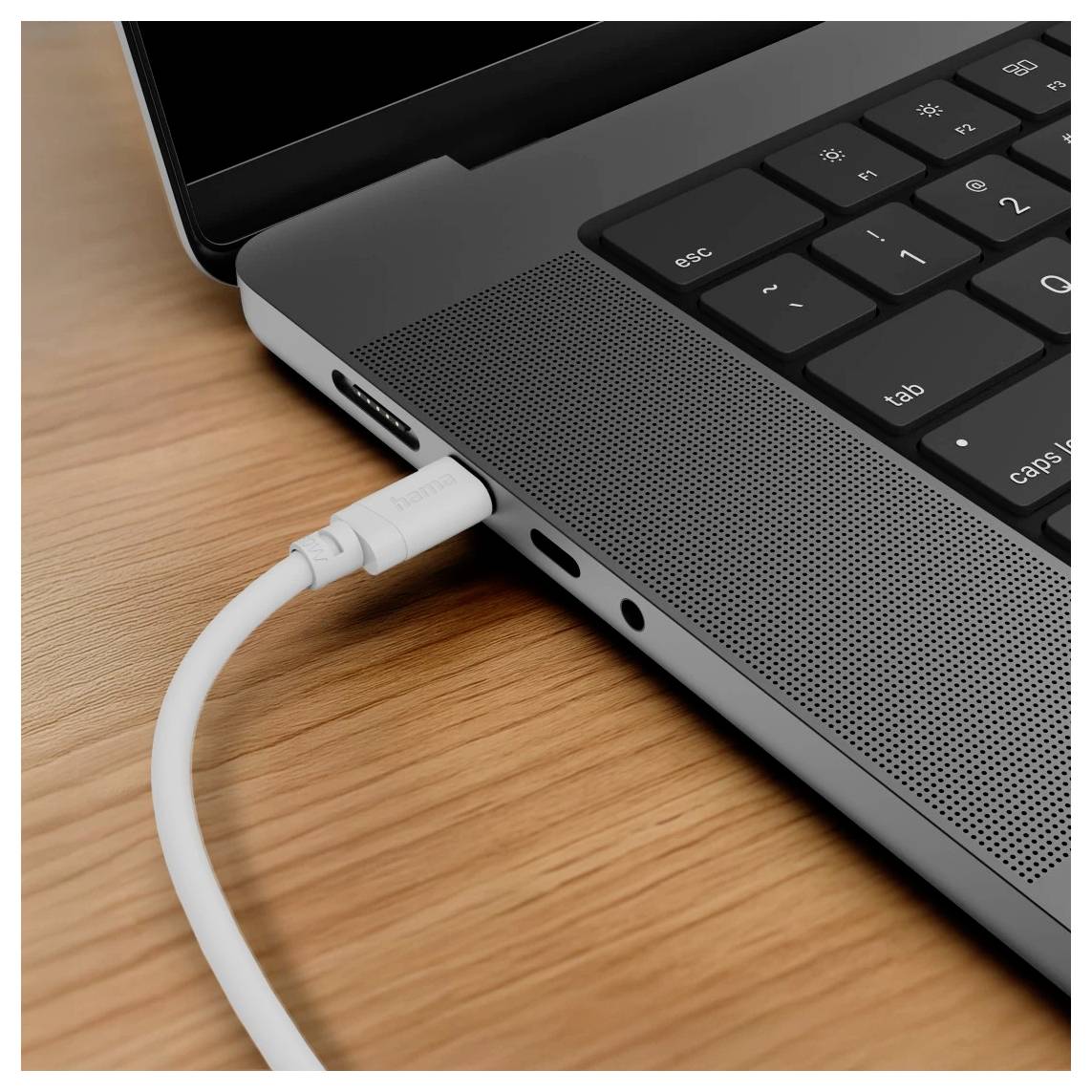 Weißes USB-C-Kabel, das in die Seite eines Laptops auf einem Holzschreibtisch gesteckt ist.