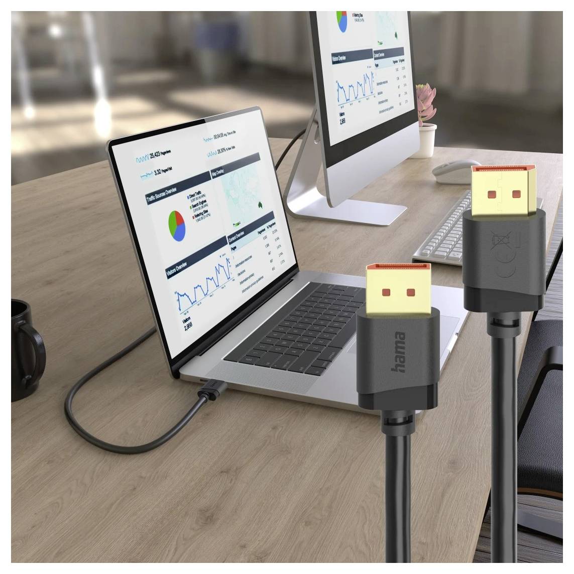 Zwei USB-C-Kabel sind an einen Laptop und einen Desktop-Monitor auf einem Schreibtisch angeschlossen, wobei die Bildschirme Analytics-Dashboards anzeigen.
