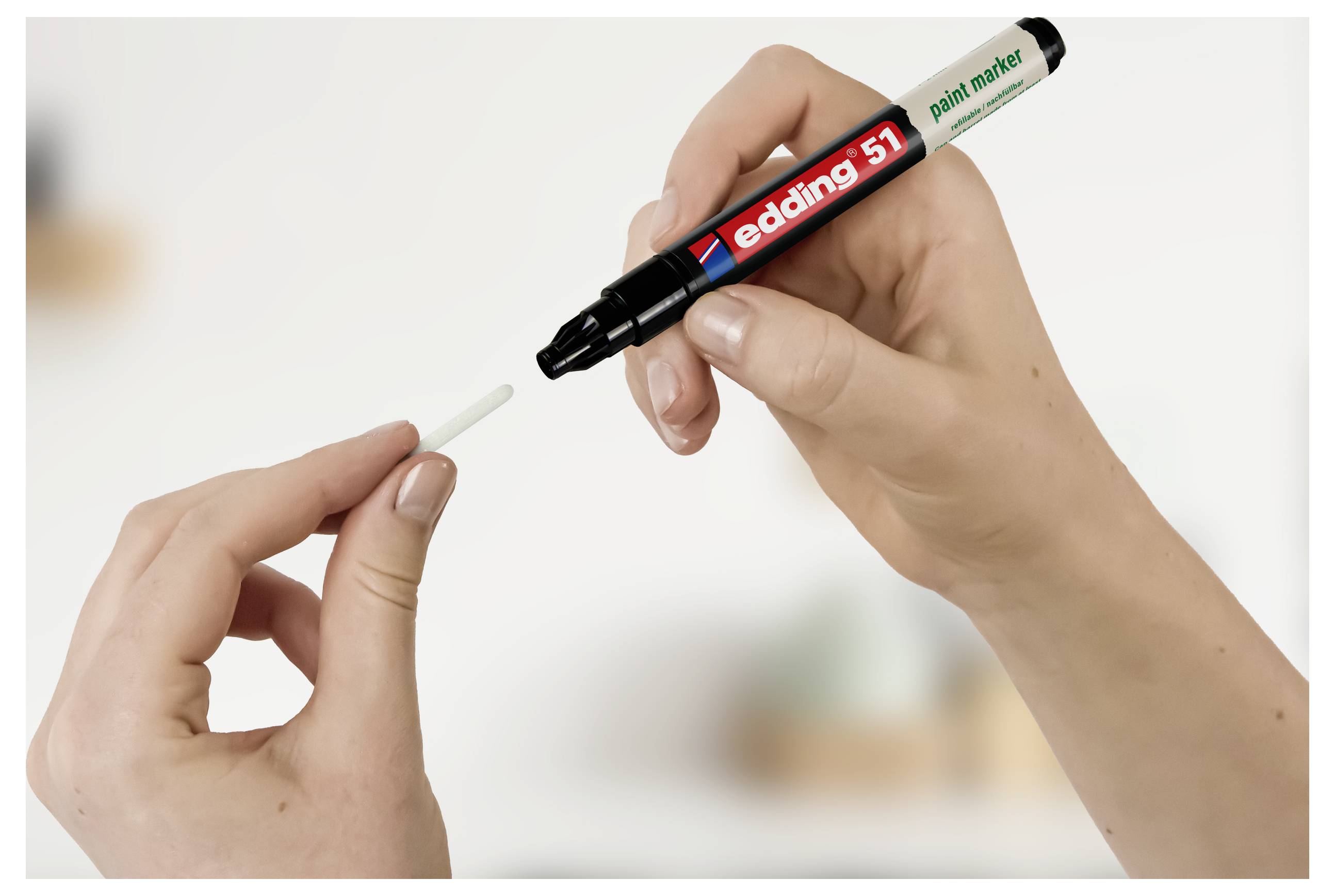 Hände, die einen weißen Lackmalstift und seine Kappe halten, demonstrieren, wie man den Stift zusammenbauen oder verwenden kann.