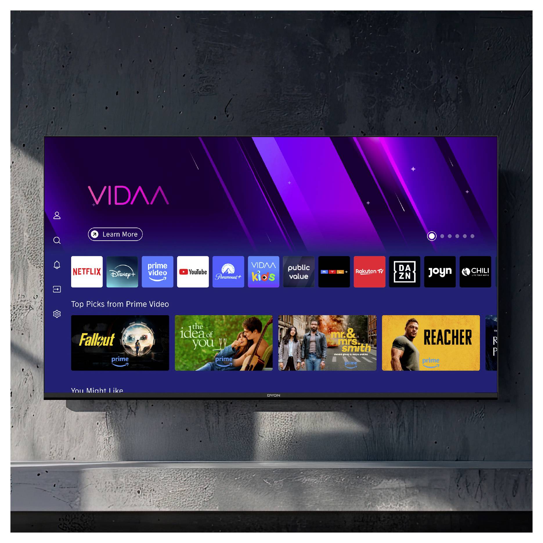 Ein an der Wand montierter Fernseher zeigt den VidAA-Startbildschirm mit App-Symbolen wie Netflix, Prime Video, YouTube und Inhaltsreihen, einschließlich Prime Video-Auswahl.