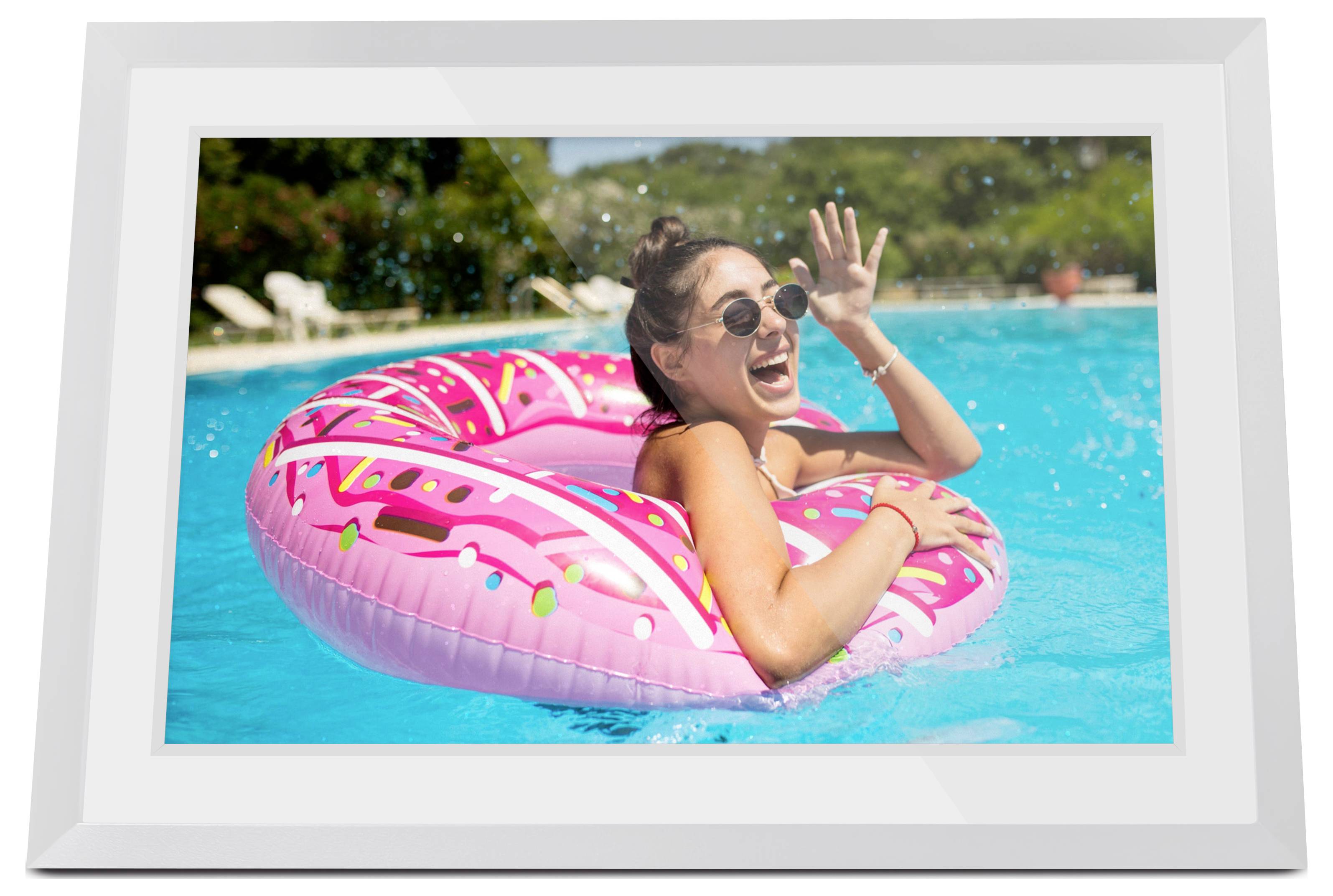 Frau, die auf einem rosafarbenen Donut-Schwimmring in einem Schwimmbecken lacht, winkt in heller Sonnenschein.