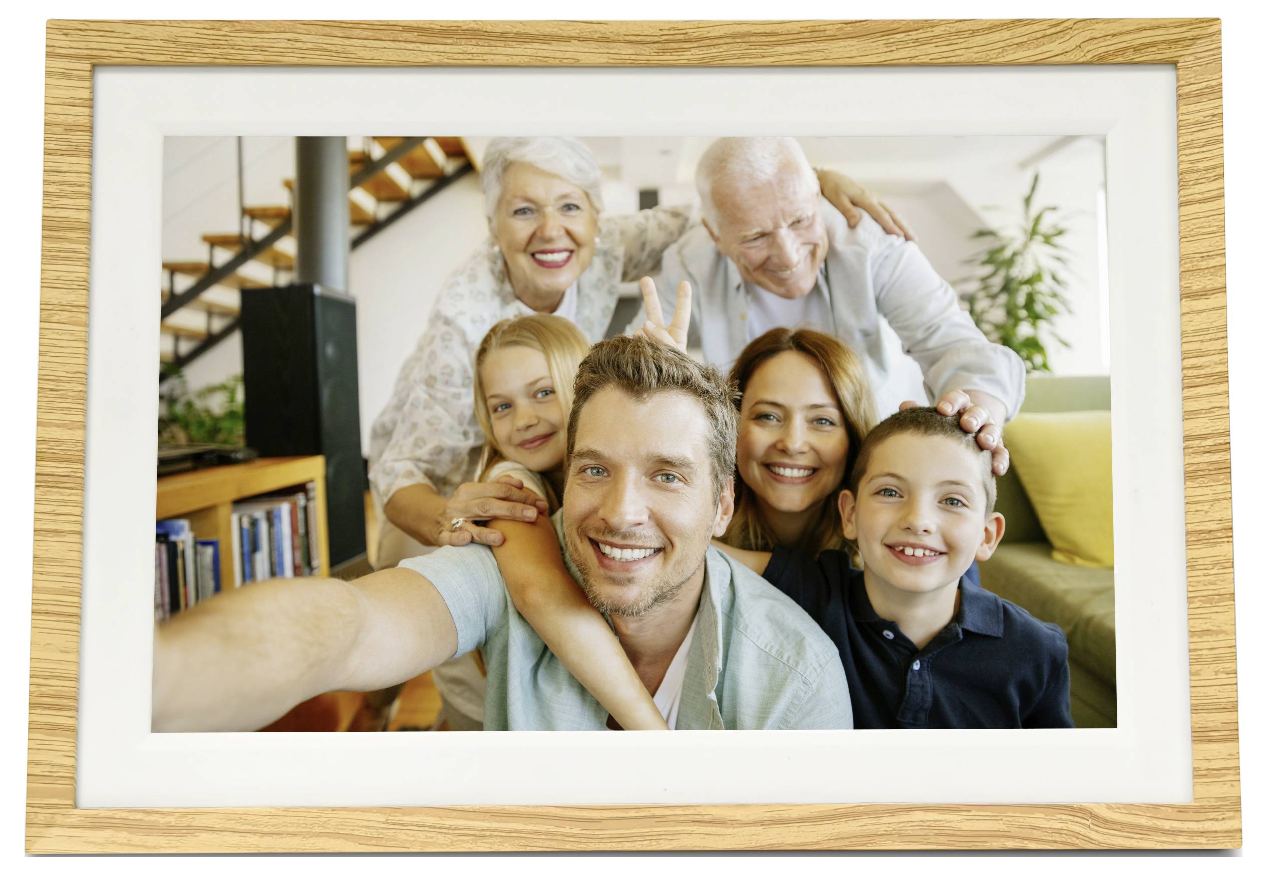 Mehrgenerationale Familie, die sich zu einem Selfie zusammenstellt, mit Großeltern, Eltern und zwei Kindern, die zusammen im Wohnzimmer lächeln.